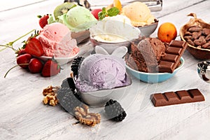 Ice cream scoops of different colors and flavours with berries, nuts and fruits decoration on white background