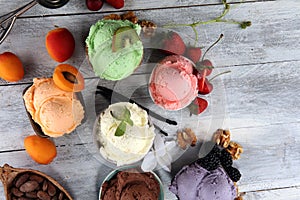 Ice cream scoops of different colors and flavours with berries, nuts and fruits decoration on white background