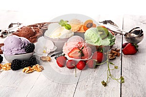 Ice cream scoops of different colors and flavours with berries, nuts and fruits decoration on white background