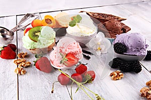 Ice cream scoops of different colors and flavours with berries, nuts and fruits decoration on white background