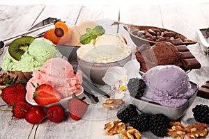 Ice cream scoops of different colors and flavours with berries, nuts and fruits decoration on white background