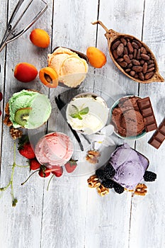 Ice cream scoops of different colors and flavours with berries, nuts and fruits decoration on white background