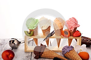 Ice cream scoops of different colors and flavours with berries, nuts and fruits decoration on white background