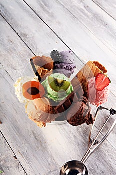 Ice cream scoops of different colors and flavours with berries, nuts and fruits decoration on white background