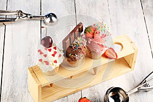 Ice cream scoops of different colors and flavours with berries, sprinkles and fruits decoration on white background