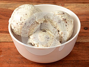 ice cream scoops served in a bowl over a rustic wooden table, selective focus