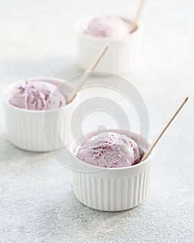 Ice cream scoops in white cups of strawberry flavours on gray background