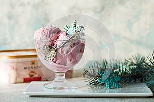 Ice cream served in a glass bowl. Displayed with candy canes on wooden rustic table. Sparkling Christmas tree lights background