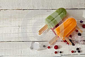 Ice cream on a stick with fruits on the light wooden table