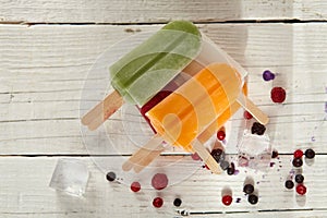 Ice cream on a stick with fruits on the light wooden table