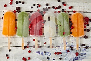Ice cream on a stick with fruits on the light wooden table