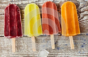 Ice cream on a stick with fruits on the light wooden table