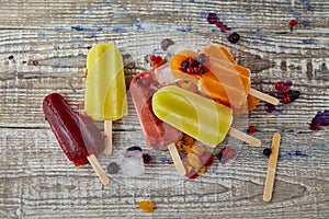 Ice cream on a stick with fruits on the light wooden table