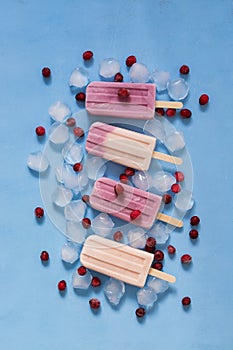 Ice cream on a stick pink and purple on a blue background. Ice cream with berries. The concept of summer. Top view, vertical. Froz