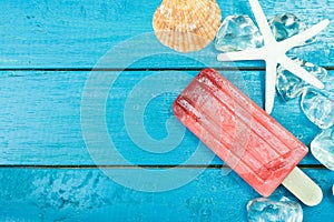 Ice cream sticks with ice and star fish on wooden background.