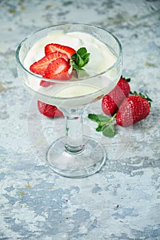 Ice cream with strawberries in a glass vase. Gray textured background. Dessert