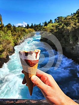 Ice cream treat while enjoying the scenic beauty of Huka Falls, New Zealand. Handheld refreshment for summer