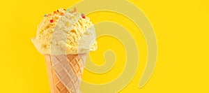 Ice cream. Vanilla, banana or lemon flavor icecream in waffle cone over yellow background. Sweet dessert