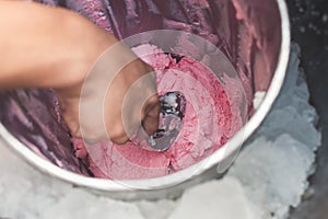 An ice cream vendor scoops strawberry sorbetes from inside a storage container. Traditional ice cream in the Philippines