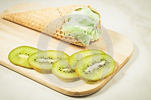 Ice cream in a wafer cup and kiwi slices/ice cream in a wafer cup and kiwi slices on a wooden tray