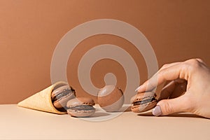 Ice-cream waffle cone with brown chocolate macaroons on beige background. Sweet food. Tasty desert. Homemade meal. Delicious food