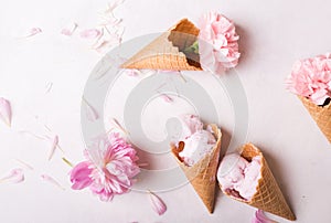 Ice cream in a waffle cone on a light background. Strawberry ice cream. Flowers in a waffle cone. Pink carnations. Flowers on a wo