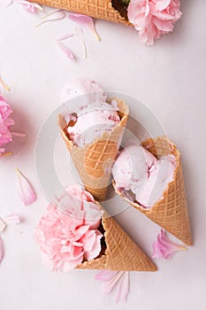 Ice cream in a waffle cone on a light background. Strawberry ice cream. Flowers in a waffle cone. Pink carnations. Flowers on a wo