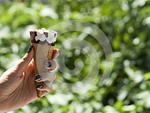 Ice cream cone in hand on blurred green background