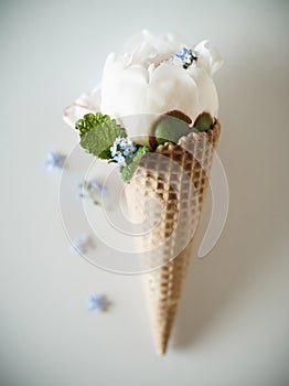 Ice creams immitation in waffle cone decorated mint leaves and flowers. Peonies flower in waffle cone with mint leaves.