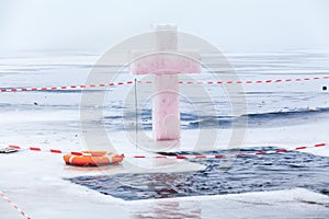 Ice cross and hole in winter pond on Epiphany