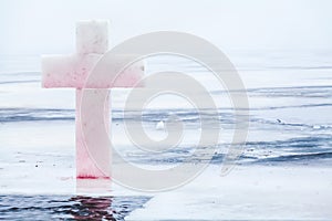 Ice cross and hole in winter pond on Epiphany