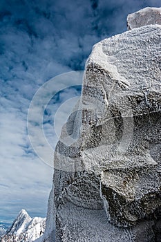 Ice crystals formed on rockface in winter against cloud sky