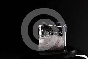 Ice cube on black background. Low key photo