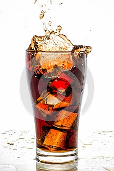 Ice cube droped in cola glass and cola splashing