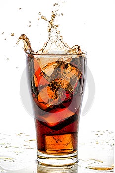 Ice cube droped in cola glass and cola splashing