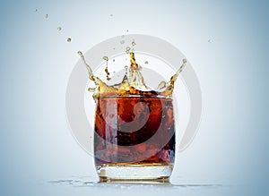 Ice cube droped in cola glass and cola splashing