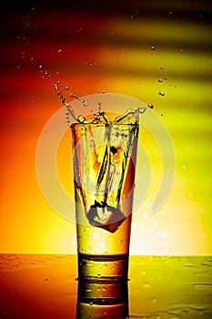 Ice cube entering a glass of water with a splash