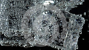 Ice cube in fizzy splashing water with soda