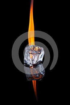 Ice cube with flame on shiny black surface