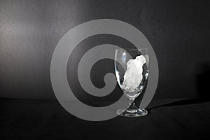 Ice cube melting in wine glass isolated in black background