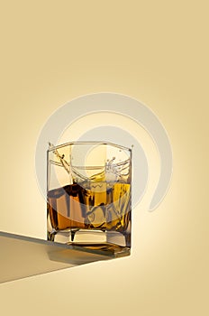 Ice cube splashing in scotch on white background