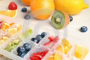 Ice cube tray with different fruits and berries on table