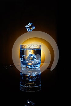 Ice cube and water splash in a clear glass.