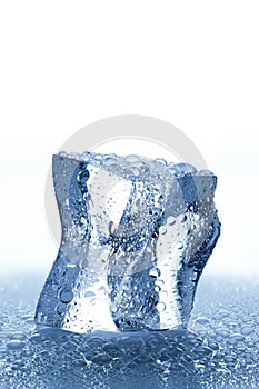 Ice cube with waterdrops melting on white background