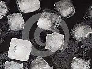 Ice cubes on black table background with water drops