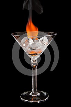 Ice cubes in glass with flame on shiny black surface