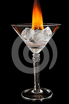 Ice cubes in glass with flame on shiny black surface