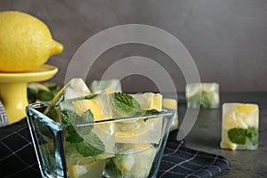 Ice cubes with mint and lemon in bowl on table