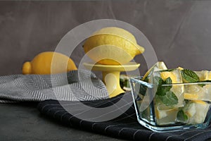 Ice cubes with mint and lemon in bowl on table.