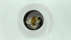 ice cubes spinning in a black glass on a white background top view.